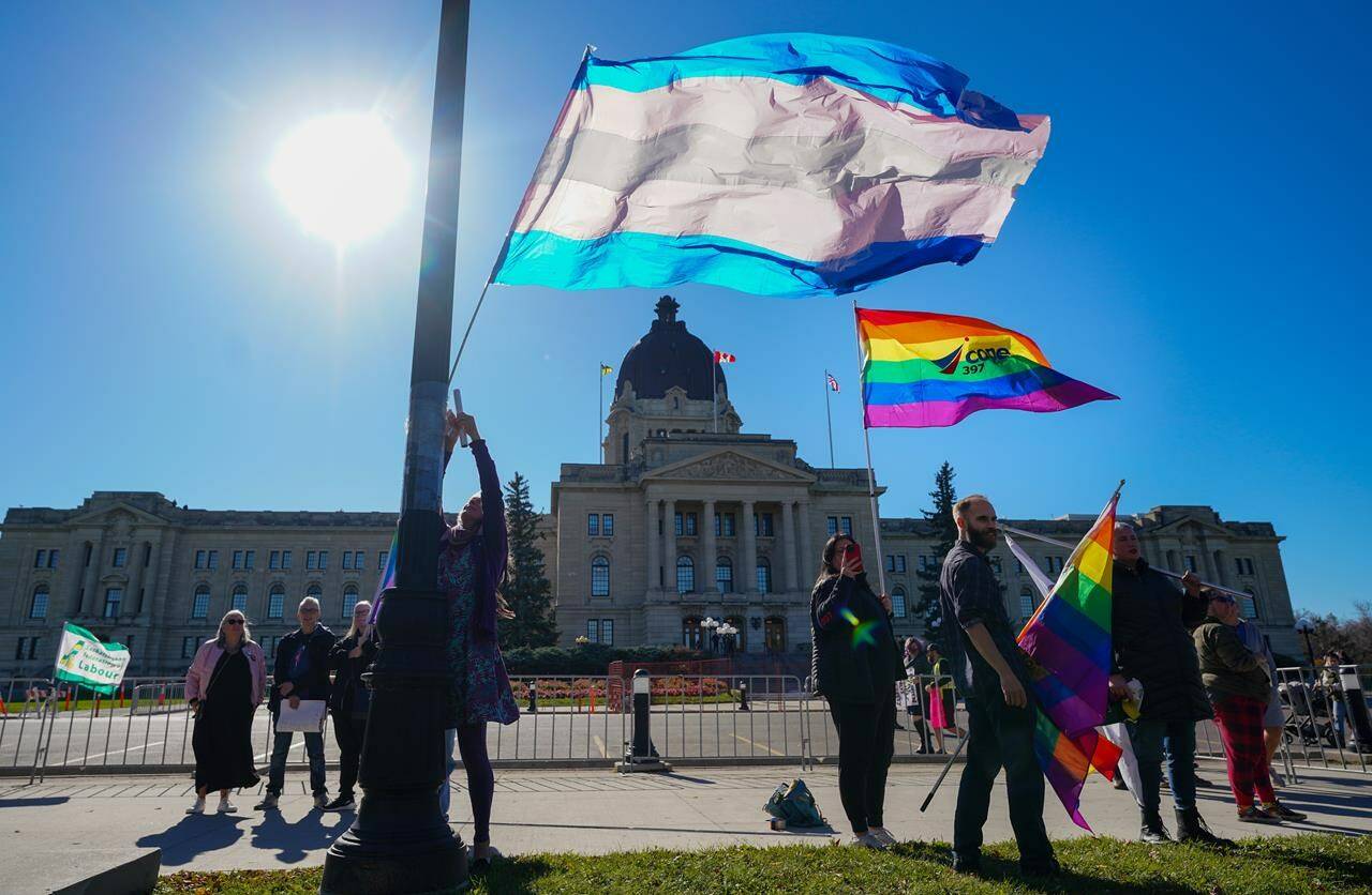 People hold pride flags while attending a rally against the Saskatchewan government’s legislation on pronouns in schools, in front of Saskatchewan legislature in Regina, on Tuesday, Oct. 10, 2023. THE CANADIAN PRESS/Heywood Yu