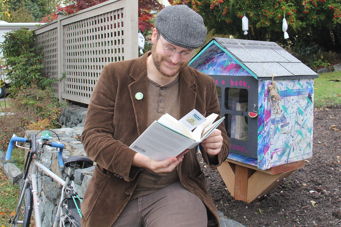 Teale Phelps Bondaroff, Greater Victoria Placemaking Network board member and Little Free Library enthusiast, stops for a read at library on Richardson Street near Oak Bay. (Black Press Media file photo)