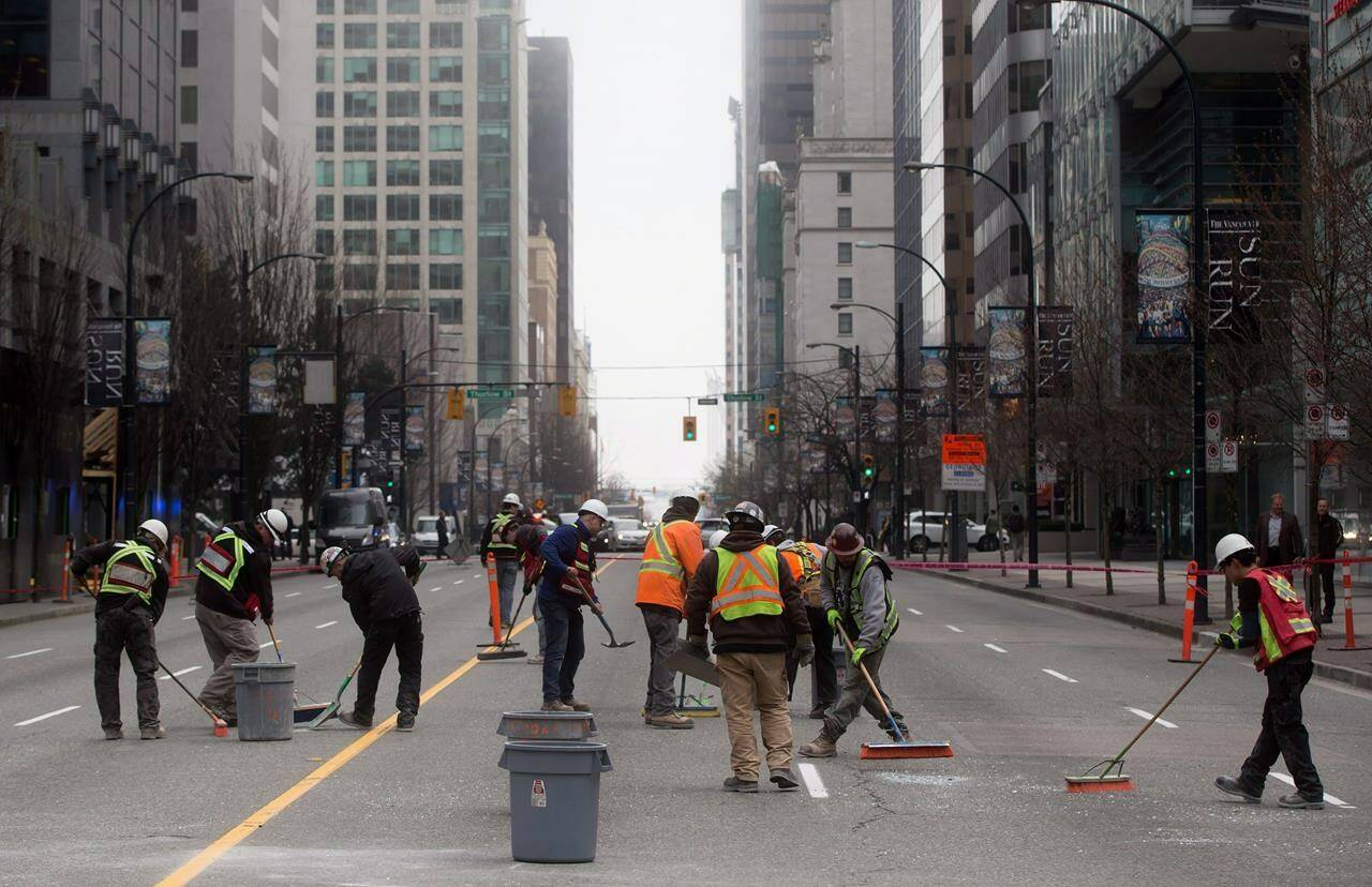 Workers sweep up broken glass after a pane of glass fell from a building under construction in Vancouver, B.C., on March 10, 2015. THE CANADIAN PRESS/Darryl Dyck