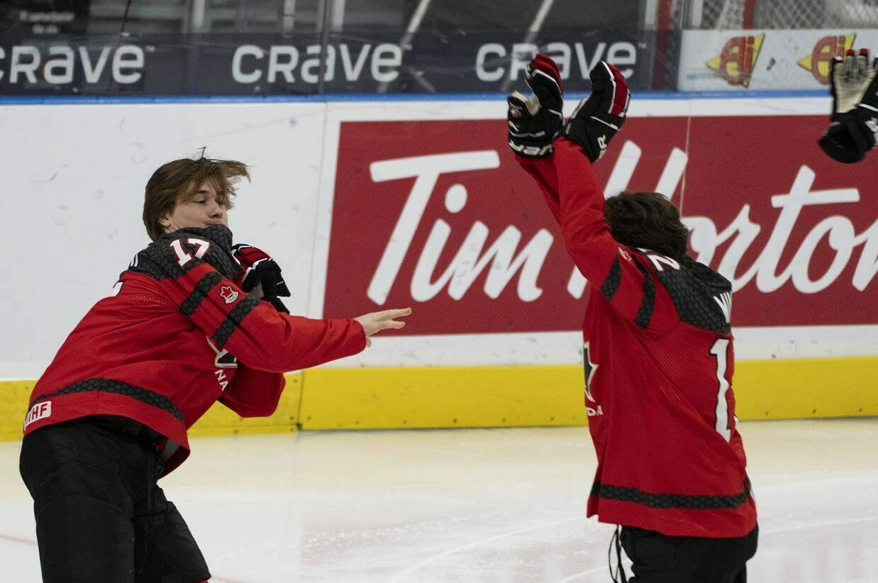 Canada’s Macklin Celebrini (17), tosses a glove past Fraser Minten (12) following the team photo at the IIHF World Junior Hockey Championship in Gothenburg, Sweden, Thursday, Dec. 28, 2023. THE CANADIAN PRESS/Christinne Muschi