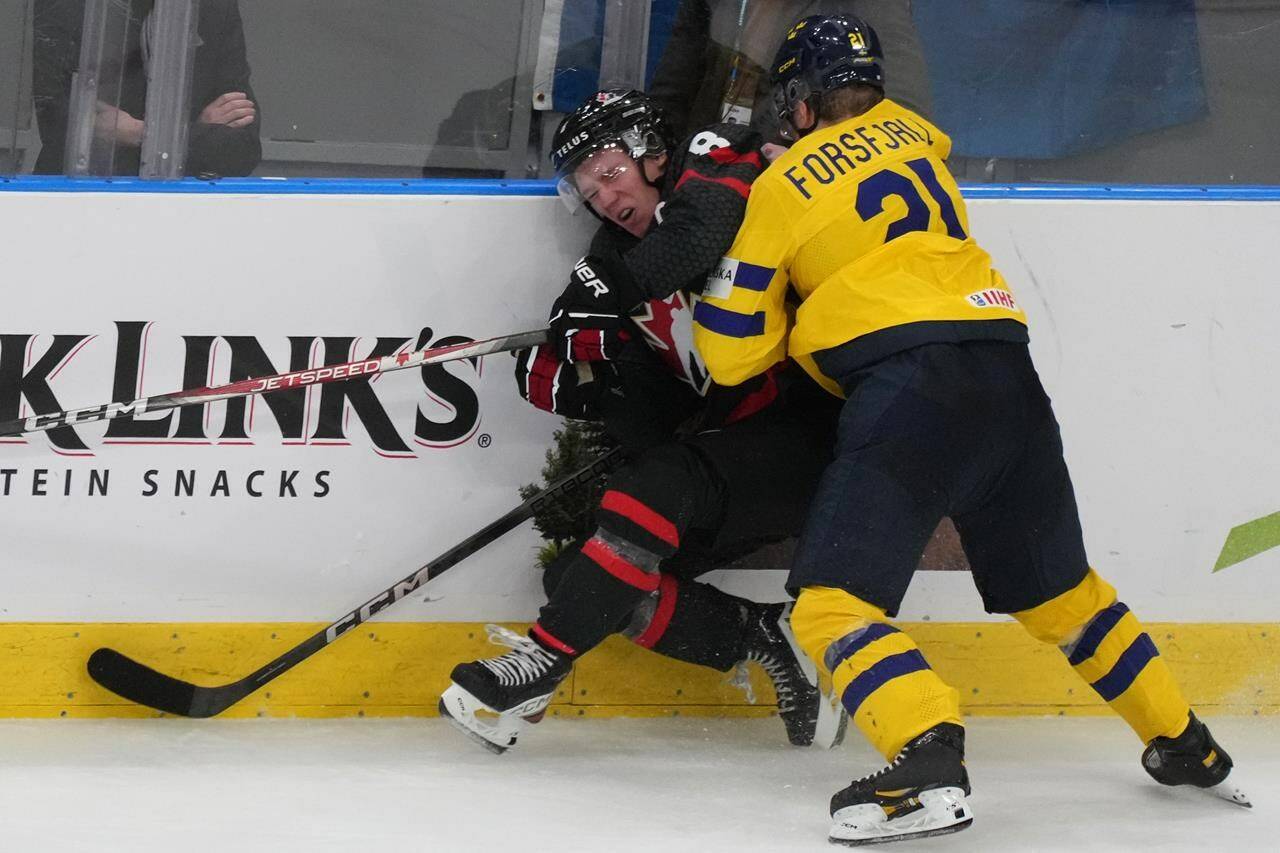 Sweden’s Zeb Forsfjall (21) pushes Canada’s Owen Beck (8) into the boards during third period preliminary round hockey action at the IIHF World Junior Hockey Championship in Gothenburg, Sweden on Friday, Dec. 29, 2023. There was no penalty called on the play. THE CANADIAN PRESS/Christinne Muschi