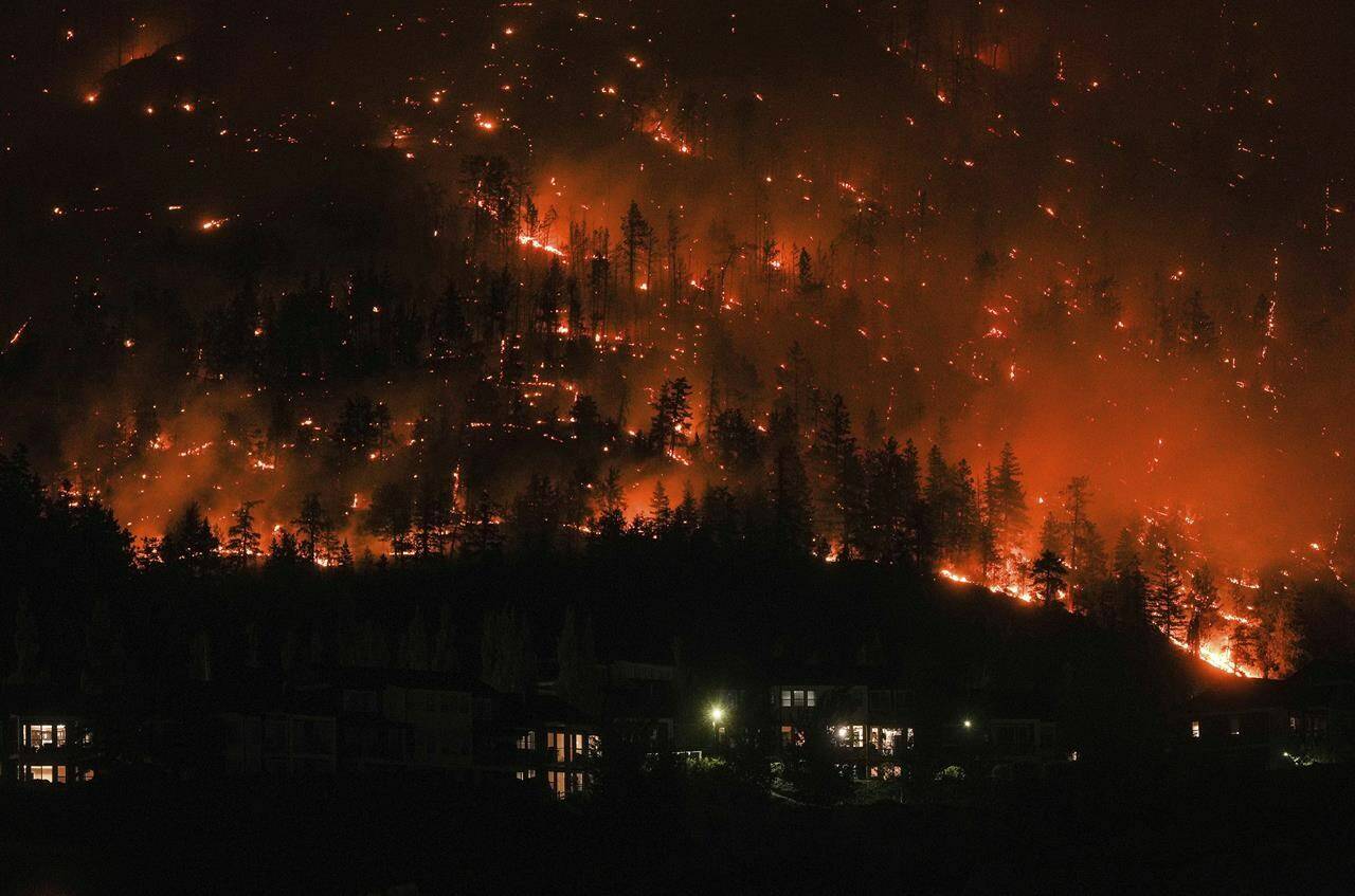 The McDougall Creek wildfire burns on the mountainside above houses in West Kelowna, British Columbia, on Aug. 18, 2023. Canada’s first-ever climate adaptation strategy was little more than six weeks old when fast-moving wildfires swept through communities in British Columbia’s southern Interior, forcing thousands to flee and destroying several hundred homes. THE CANADIAN PRESS/Darryl Dyck
