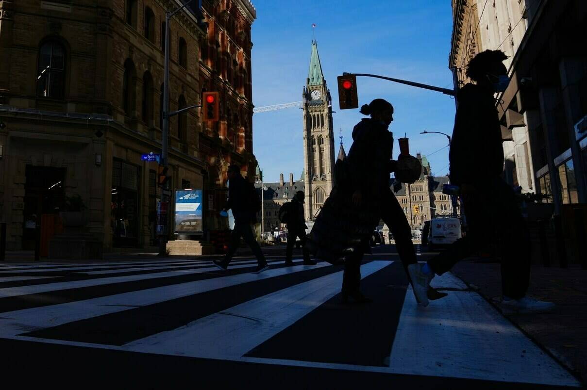 The Canadian flag flies on the Peace Tower of Parliament Hill as pedestrians make their way along Sparks Street Mall in Ottawa on Tuesday, Nov. 9, 2021. For more than a year, Canada has been mulling creation of a foreign agent registry to fight interference in the country’s democratic processes. THE CANADIAN PRESS/Sean Kilpatrick