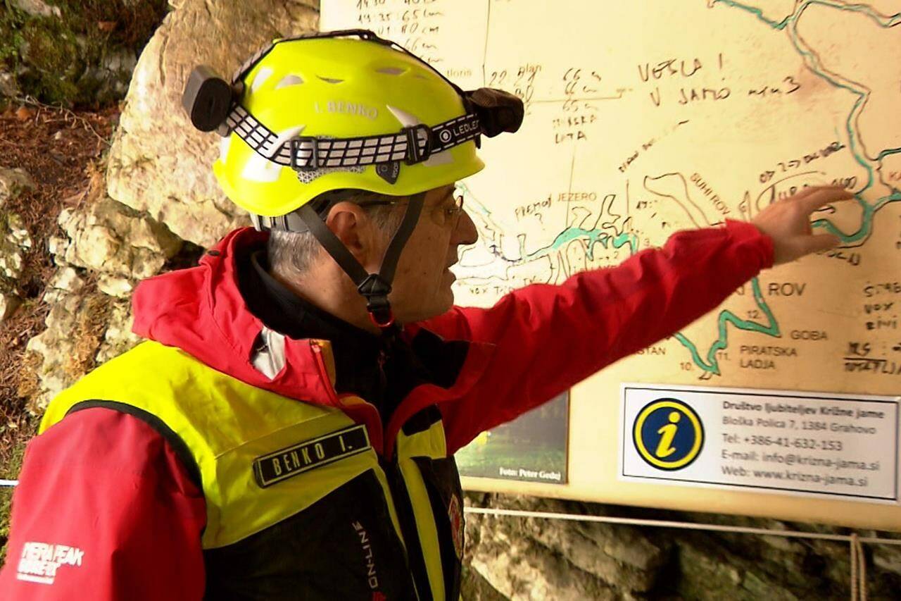 In this photo taken from video, a rescuer inspects the map of Krizna Jama cave near Grahovo, Slovenia, Sunday, Jan. 7, 2024. Slovenian authorities say five people are trapped in a cave in the southwest of the country because of high water levels caused by heavy rainfall. The group includes a family of three and two guides who have been stuck in the Krizna Jama cave since Saturday when water levels rose inside, blocking the way out. (Pop TV via AP)