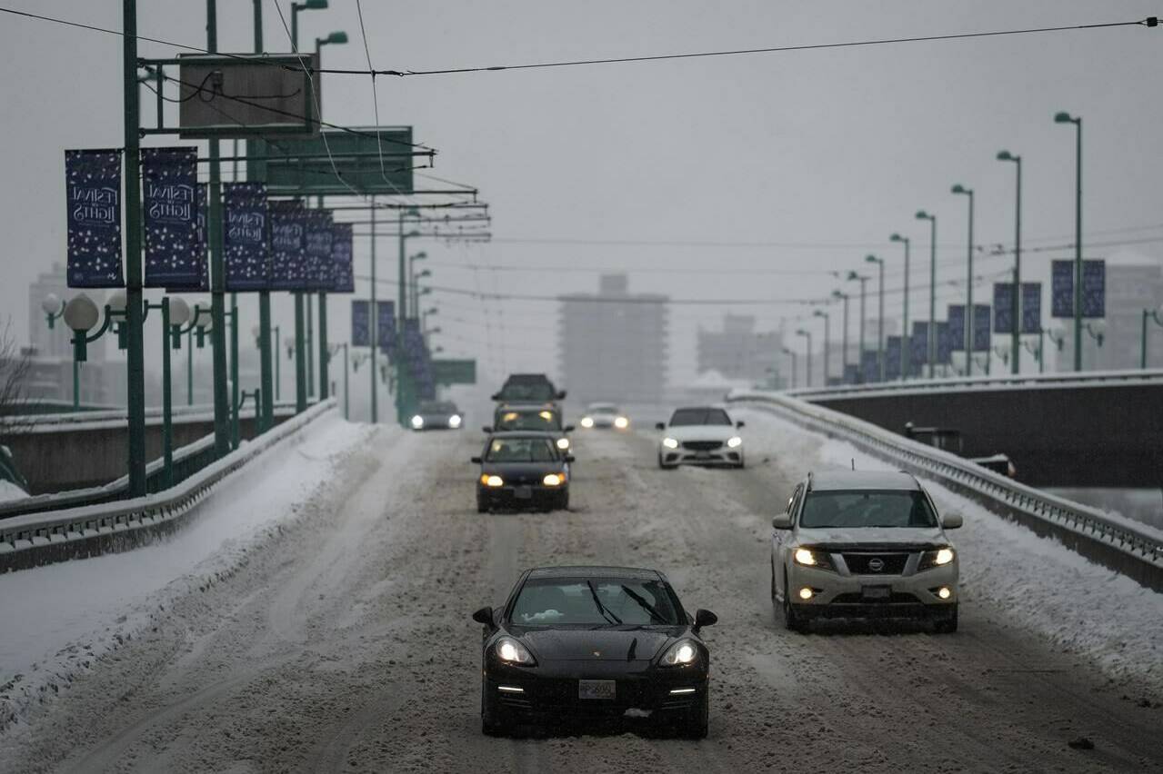 Motorists travel on the snow-covered Cambie Bridge as freezing rain falls in Vancouver, on Friday, Dec. 23, 2022. THE CANADIAN PRESS/Darryl Dyck