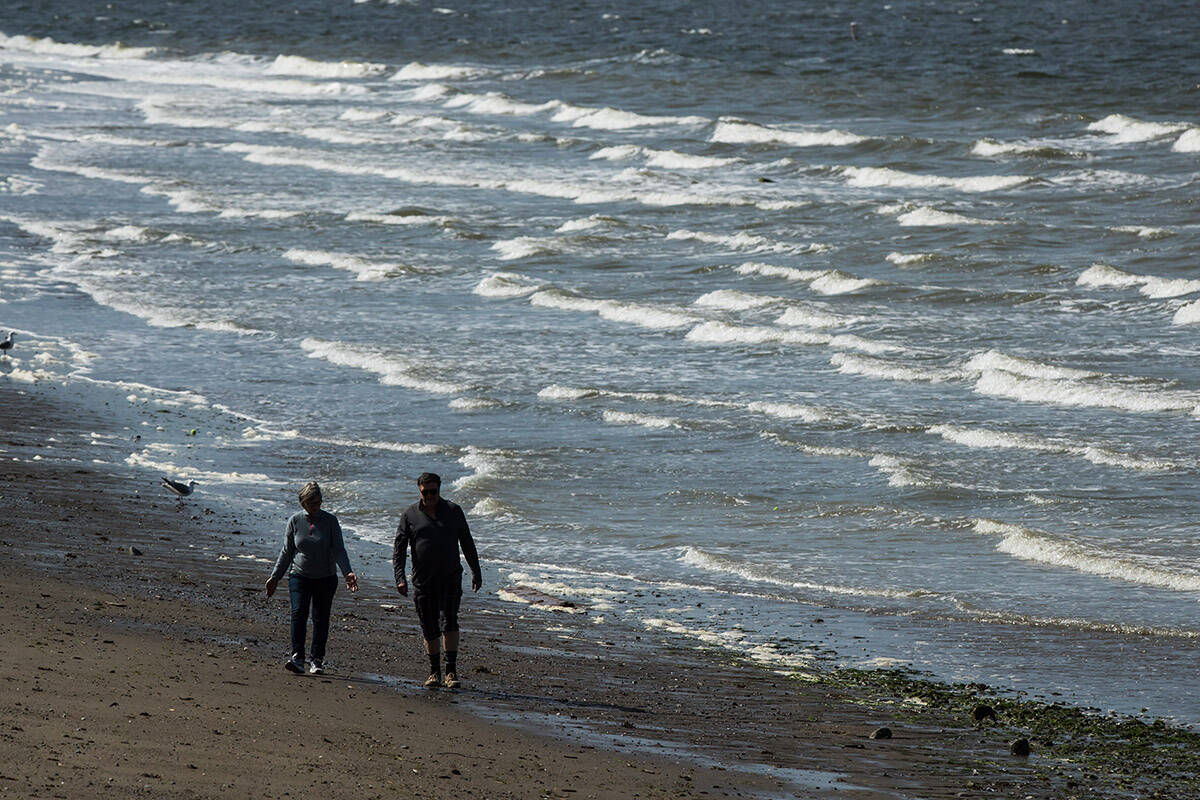 Strong winds whip up waves as a woman and man walk along the beach at English Bay in Vancouver, on Sunday May 5, 2019. Environment Canada is warning of gale-force winds in the Lower Mainland Tuesday morning, Jan. 9, 2024. THE CANADIAN PRESS/Darryl Dyck