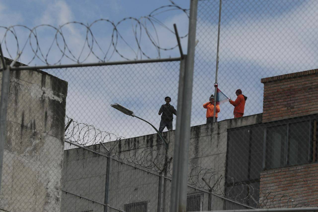 Inmates stand on the top of Turi jail during a prisoner riot in Cuenca, Ecuador, Tuesday, Jan. 9, 2024. On Monday, President Daniel Noboa decreed a national state of emergency for 60 days, allowing the authorities to suspend rights and mobilize the military in places like prisons. (AP Photo/Xavier Caivinagua)