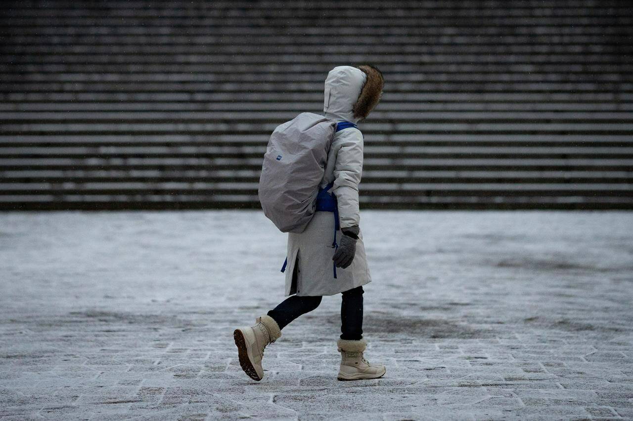 A person bundled up walks during some brief snow in Vancouver on Thursday, Jan. 11, 2024. Extreme cold and biting wind has gripped Western Canada and it won’t shake loose until at least Saturday. THE CANADIAN PRESS/Ethan Cairns