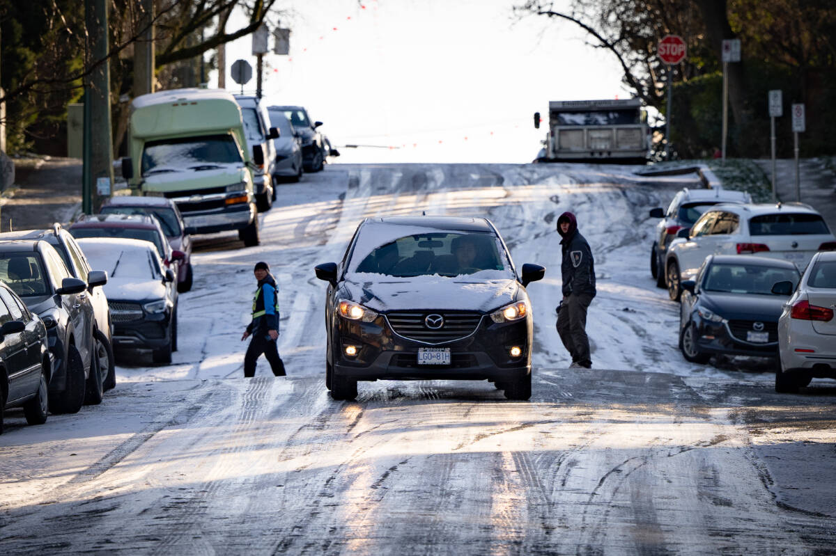 People watch as a car tries to drive down an icy hill in Vancouver on Friday, Jan. 12, 2024. Weather warnings for cold temperatures have been advised in B.C. THE CANADIAN PRESS/Ethan Cairns