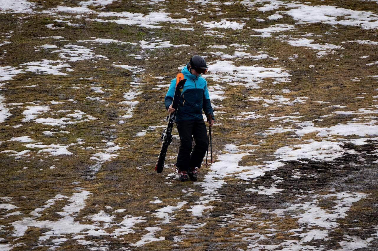 A skier walks down a patchy ski slope at Whistler, B.C., on Friday, December 29, 2023. Whistler has been experiencing warm weather and little snow this season, contributing to poor snow sports conditions during peak season. THE CANADIAN PRESS/Ethan Cairns