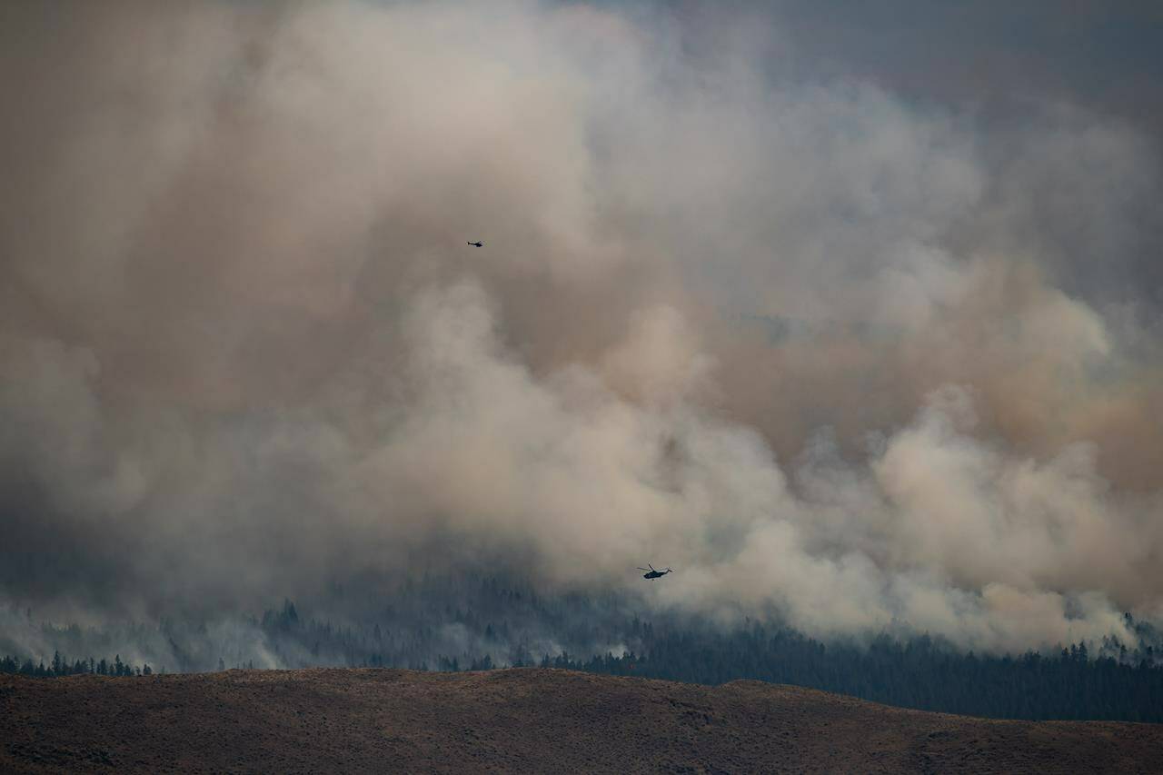 Helicopters fly past the Tremont Creek wildfire as it burns on the mountains above Ashcroft, B.C., on Friday, July 16, 2021. THE CANADIAN PRESS/Darryl Dyck