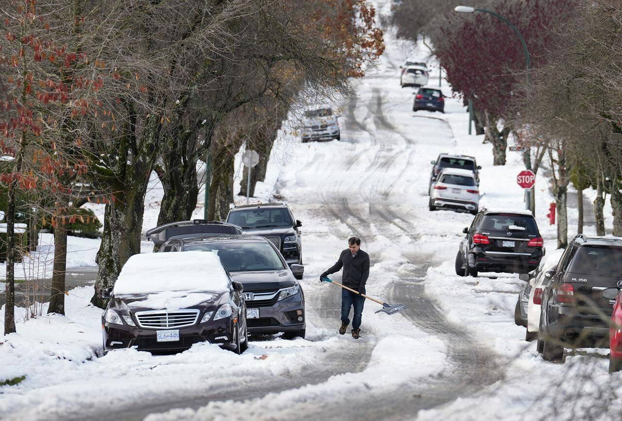 FILE — A man pauses while digging out snow from under a car stuck on a street in the aftermath of a snowstorm, in Vancouver, B.C., Wednesday, Nov. 30, 2022. THE CANADIAN PRESS/Darryl Dyck