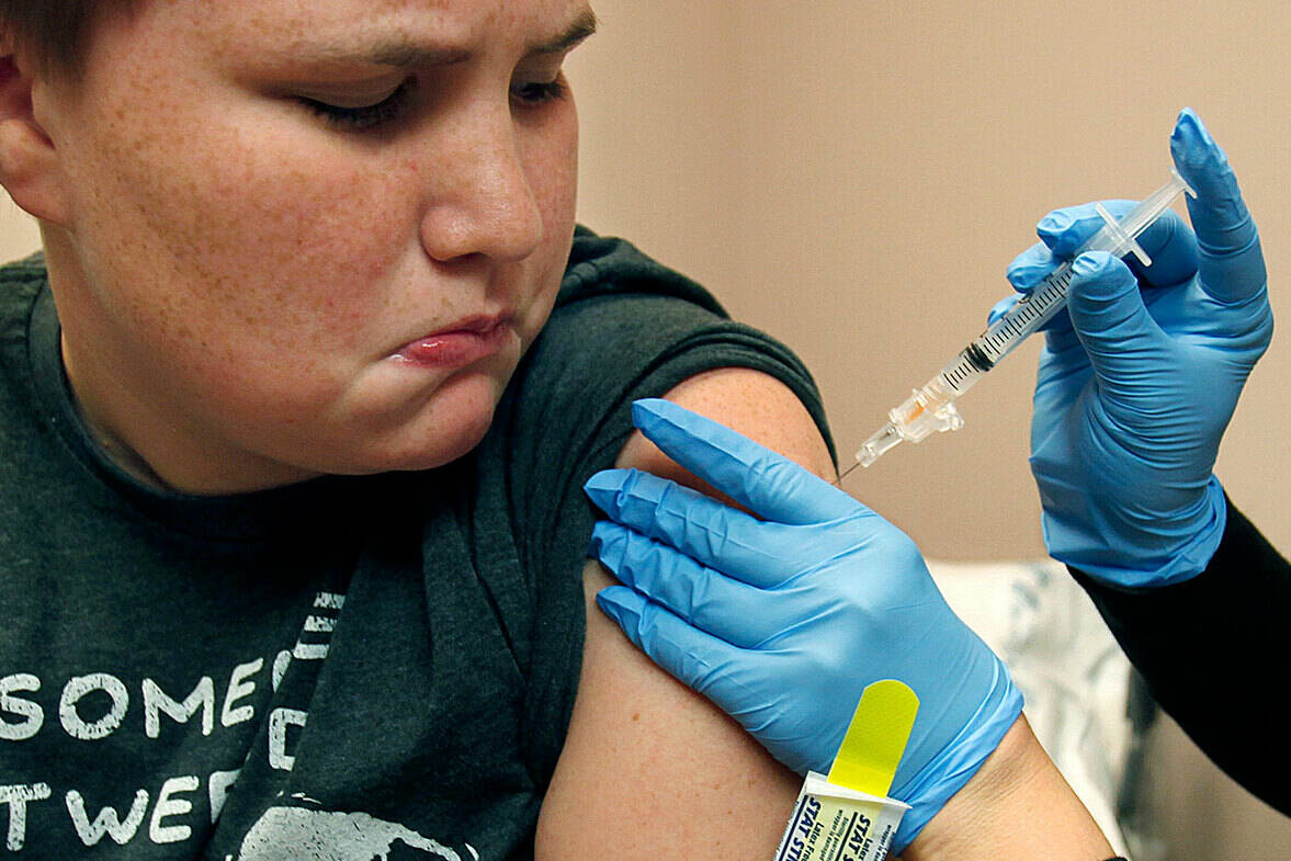 Benjamin Munn, 12, watches the needle as medical assistant Megan Smith gives him a shot of HPV vaccine at the Providence Medical Group in Monroe, July 12. There are a number of benefits in giving boys the vaccine at an early age. Dan Bates / The Herald