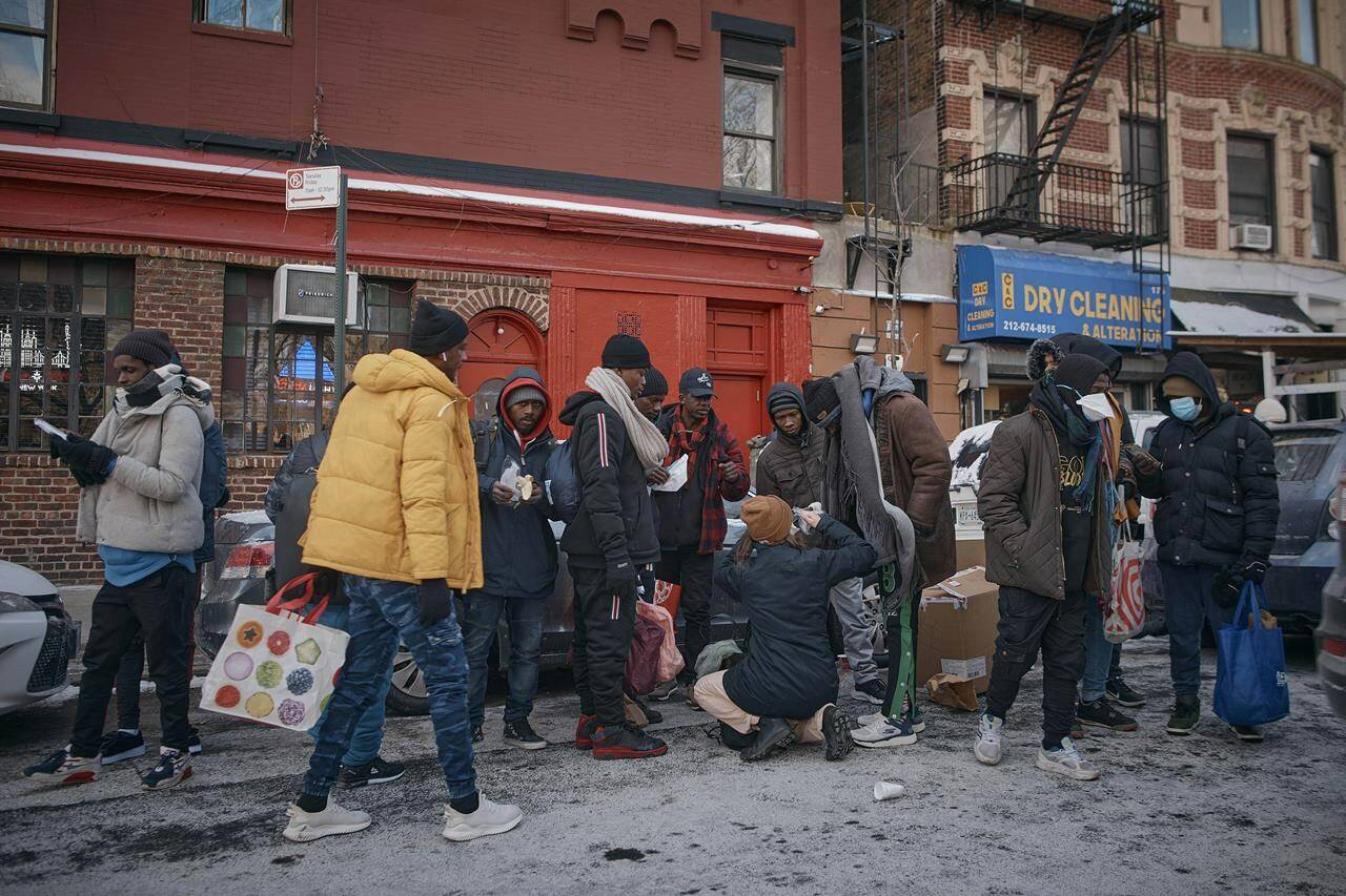 Migrants pick up clothes as mutual aid groups distribute food and clothes under cold weather near the Migrant Assistance Center at St. Brigid Elementary School, on Saturday, Jan. 20, 2024, in New York. (AP Photo/Andres Kudacki)