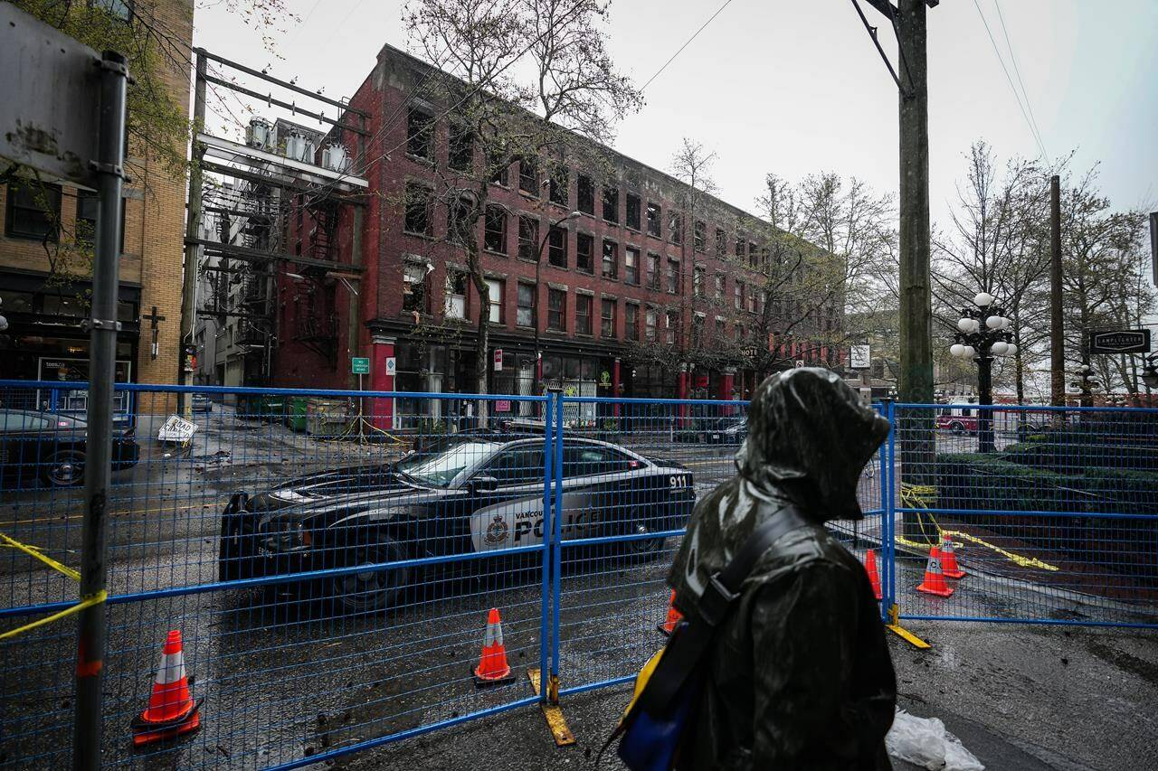 A coroner’s inquest has been told that a Vancouver rooming house where a fire killed two people in 2022 had a chained door, as relatives testified about the devastating impact of the blaze. A police officer sits in a vehicle outside of the Winters Hotel that was destroyed by fire in Vancouver on Tuesday, April 12, 2022. THE CANADIAN PRESS/Darryl Dyck