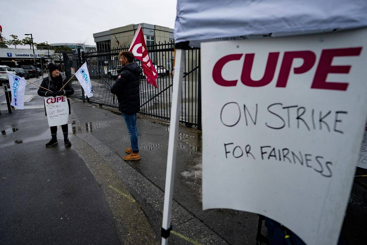 Transit workers from the Canadian Union of Public Employees Local 4500 picket outside of the Lonsdale SeaBus station in the rain during a strike in North Vancouver, B.C., on Monday, Jan. 22, 2024. THE CANADIAN PRESS/Ethan Cairns