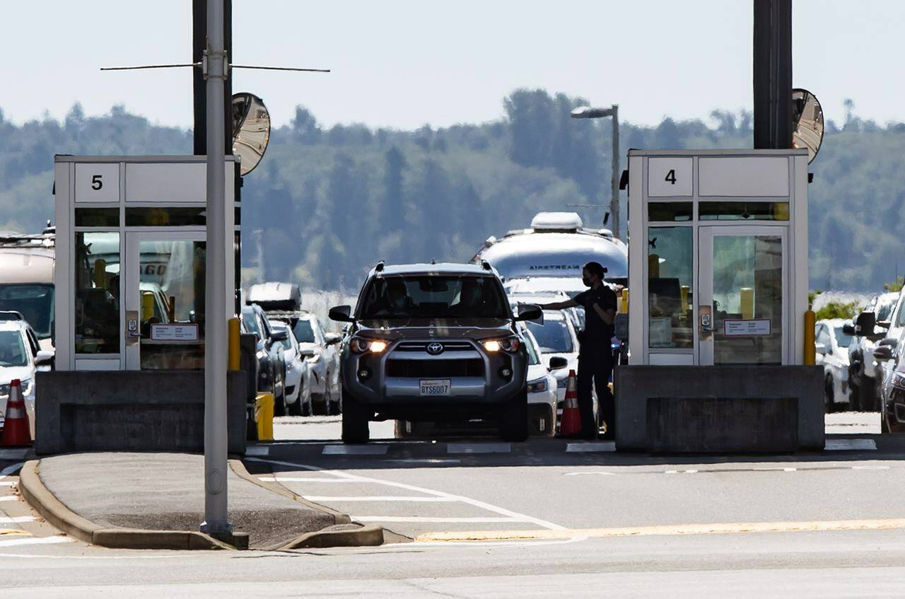 A Canada Border Services Agency officer hands documents back to a motorist entering Canada at the Douglas-Peace Arch border crossing, in Surrey, B.C., on Monday, Aug. 9, 2021. THE CANADIAN PRESS/Darryl Dyck