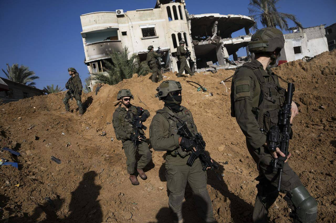 Israeli army troops are seen next to a destroyed building during a ground operation in Khan Younis, Gaza Strip, on Wednesday, Jan. 10, 2024. THE CANADIAN PRESS/AP-Ohad Zwigenberg