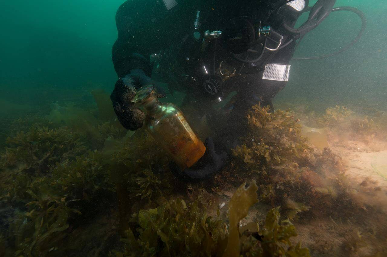 FILE — Parks Canada diver Brandy Lockhart picks up a decanter bottle recovered from the HMS Erebus during a dive in August of 2019 in this handout photo. THE CANADIAN PRESS/HO, Charles Dagneau, Parks Canada **