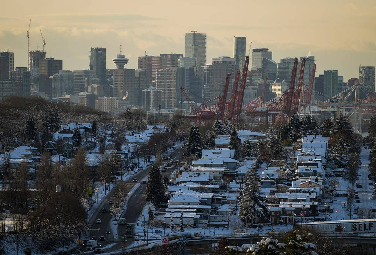 Houses are covered with snow as the downtown skyline is seen in the distance, in Vancouver, on Wednesday, December 21, 2022. The province has expanded its secondary suite program to 16 regional districts, according to a news release Jan. 30, 2024. THE CANADIAN PRESS/Darryl Dyck
