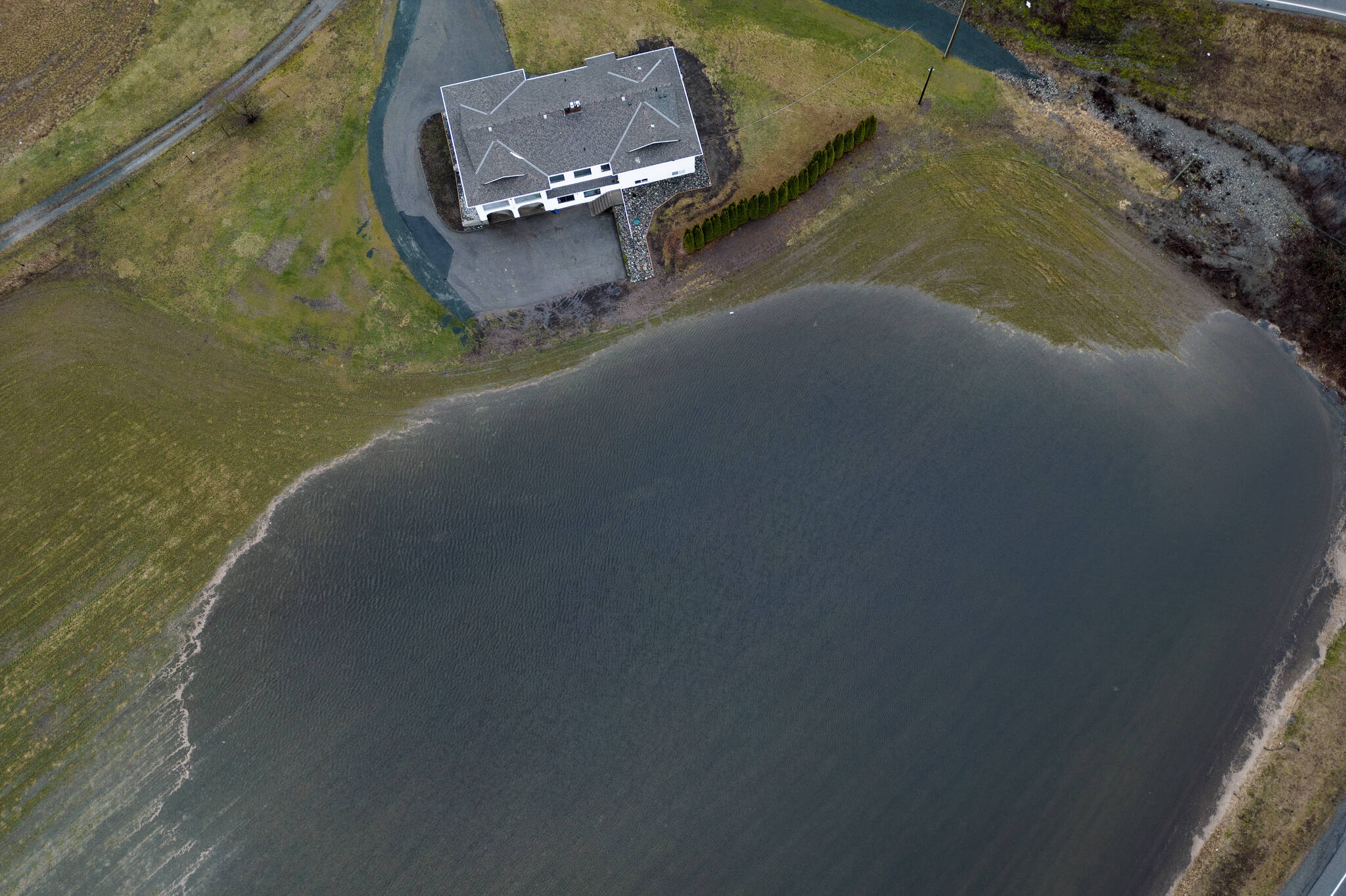 In this photograph taken with a drone; a large amount of water floods a low area of a farm near a house in Abbotsford, B.C., Wednesday, Jan. 31, 2024. A weather system with unseasonable warmth has melted snow and brought drenching rain to the province with temperatures reaching 18C in parts of B.C.’s Lower Mainland this week. THE CANADIAN PRESS/Darryl Dyck