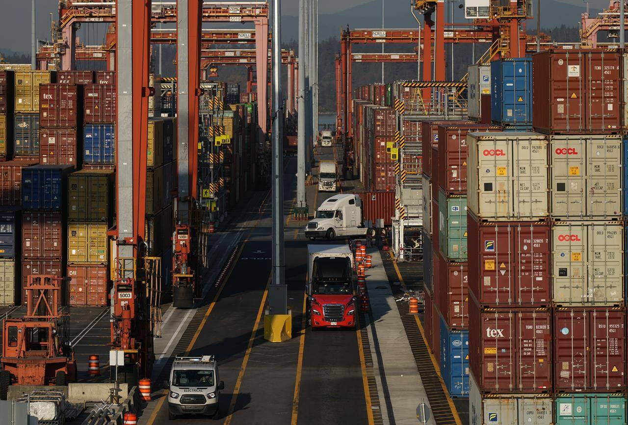 Cargo containers are moved by trucks at the Port of Vancouver Centerm container terminal as others are stacked under gantry cranes, in Vancouver, on Friday, Oct. 14, 2022. THE CANADIAN PRESS/Darryl Dyck
