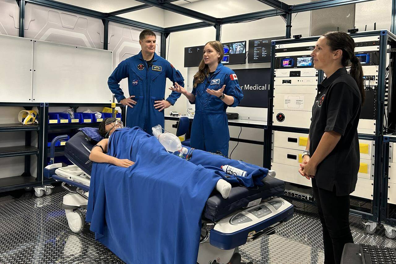 Astronauts Jeremy Hansen, left, and Jenni Gibbons, centre, take part in a demonstration on how astronauts will receive medical care during long-duration space missions and how that can be applied in remote regions here on Earth at the Canadian Space Agency in Longueuil, Quebec on Monday Feb. 5, 2024. Annie Martin, right, a Canadian Space Agency manager looks on during the demonstration. THE CANADIAN PRESS/Sidhartha Banerjee