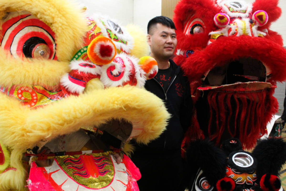 Teacher Justin Lee stands beside his suited-up lion dancer students at practice before the Grand Parade in Chinatown. (Ella Matte/News Staff)
