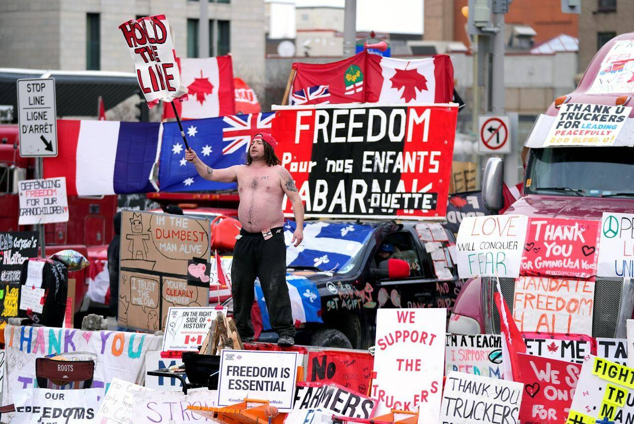 Representatives of the so-called Freedom Convoy are planning to hold a press conference in Ottawa this afternoon, two years after the police action that ended the occupation of downtown Ottawa streets. A protester dances on a concrete jersey barrier in front of vehicles and placards on Rideau Street in Ottawa, on Wednesday, Feb. 16, 2022. THE CANADIAN PRESS/Justin Tang