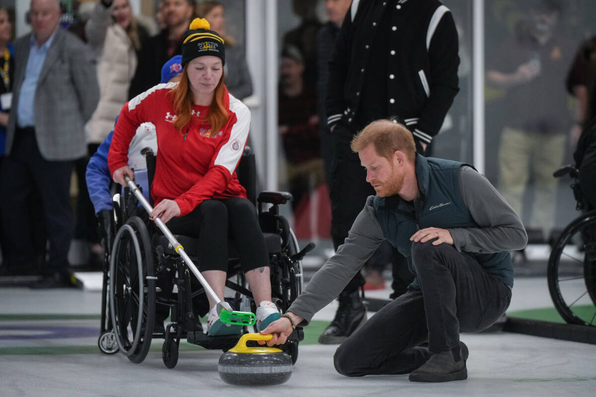 Prince Harry, the Duke of Sussex, slides a curling rock into place for Emilie Poulin as she prepares take a shot during an Invictus Games wheelchair curling training camp, in Vancouver, B.C., Friday, Feb. 16, 2024. Invictus Games Vancouver Whistler 2025 is scheduled to take place from Feb. 8 to 16, 2025 and will for the first time feature winter sports. THE CANADIAN PRESS/Darryl Dyck