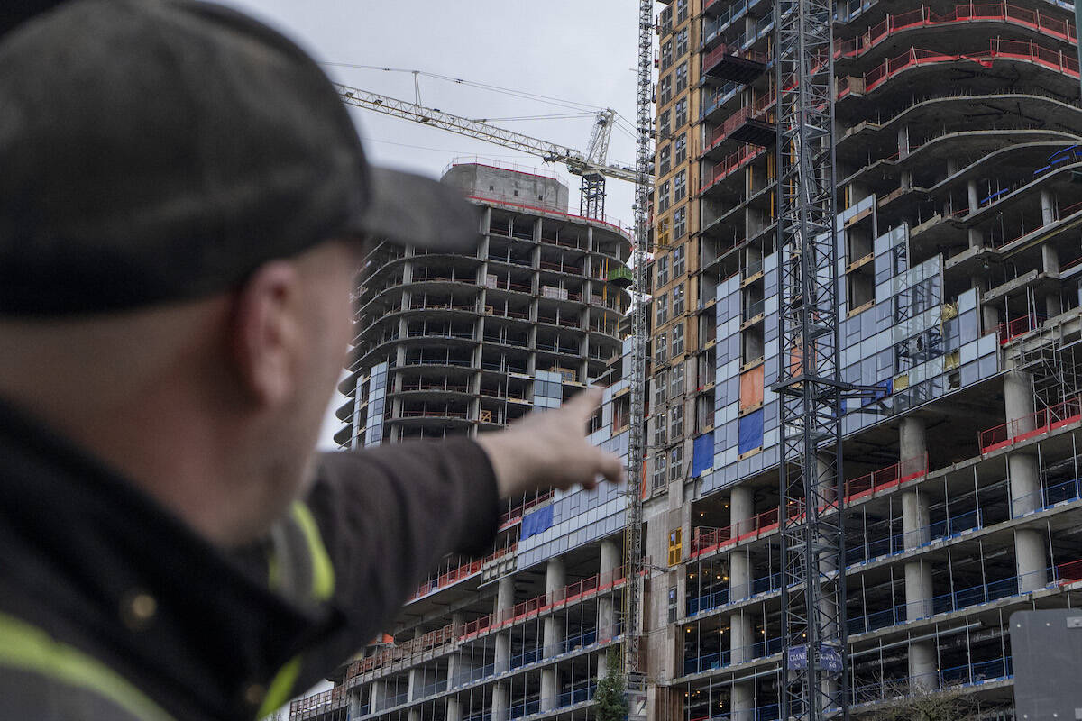 A man points at damage after a load from a crane fell from the top of the building smashing multiple floors of the Oakridge Mall construction in Vancouver, B.C. on Wednesday, Feb. 21, 2024. THE CANADIAN PRESS/Ethan Cairns