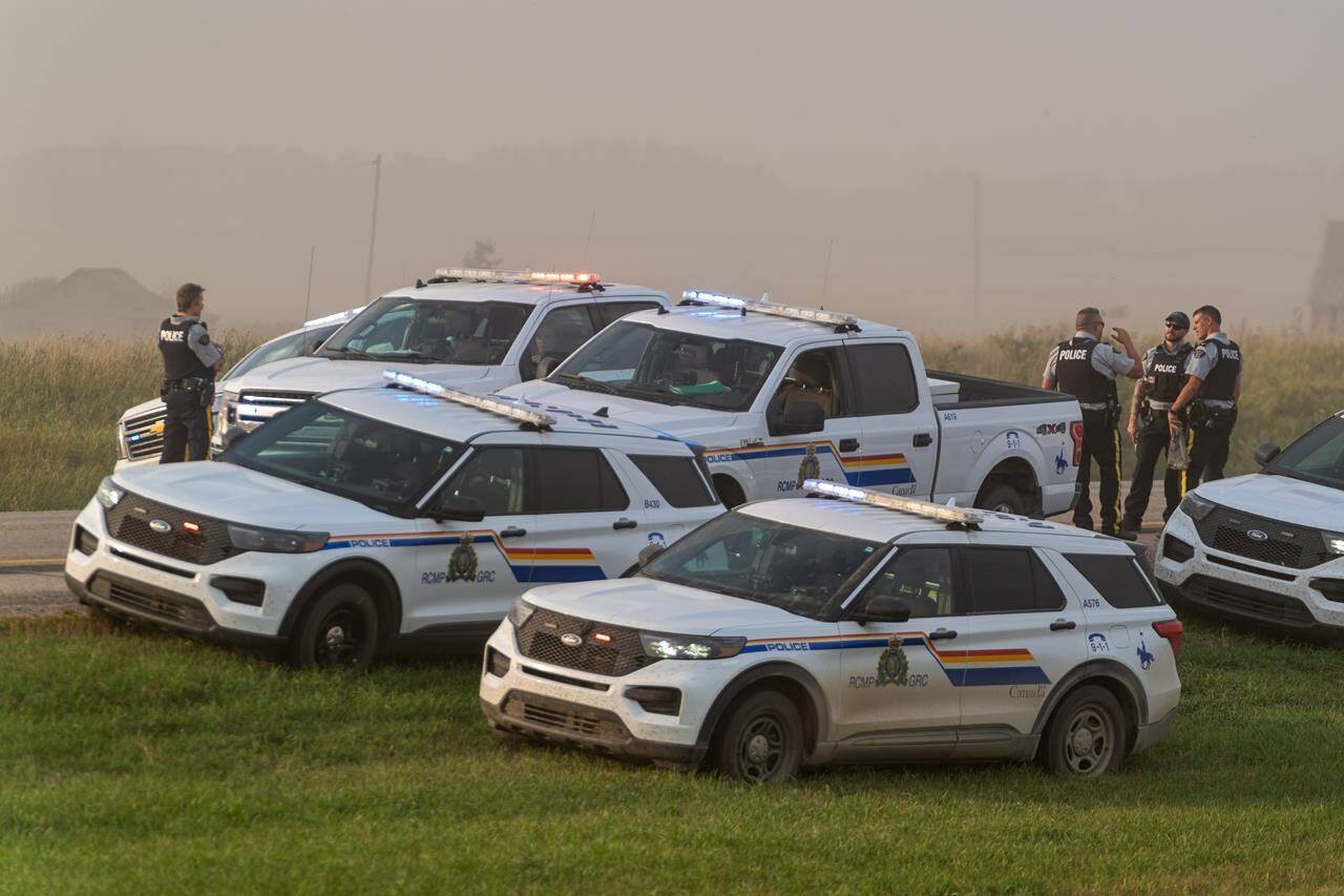 Police and investigators are seen at the side of the road outside Rosthern, Sask., on Wednesday, Sept. 7, 2022. RCMP say Myles Sanderson was taken into custody near Rosthern on the fourth day of a massive manhunt after a stabbing rampage that left 11 people dead and 18 injured. THE CANADIAN PRESS/Heywood Yu