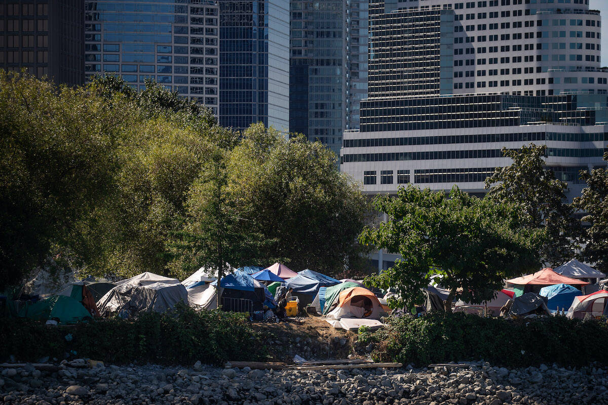 Tents and people are seen at a homeless encampment at Crab Park below the towers of the downtown skyline in Vancouver, on Sunday, August 14, 2022. THE CANADIAN PRESS/Darryl Dyck