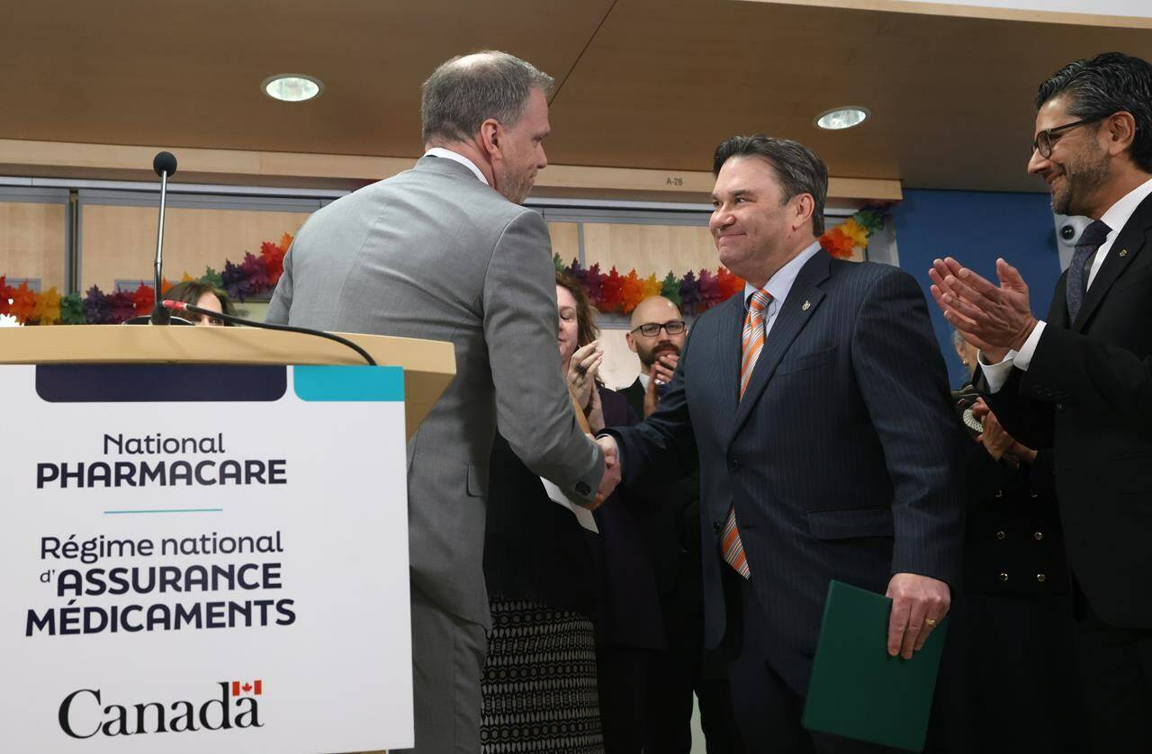 Minister of Health Mark Holland, left, shakes hands with NDP MP for Vancouver Kingsway Don Davies during a press conference about new national pharmacare legislation, in Ottawa on Thursday, Feb. 29, 2024. THE CANADIAN PRESS/ Patrick Doyle