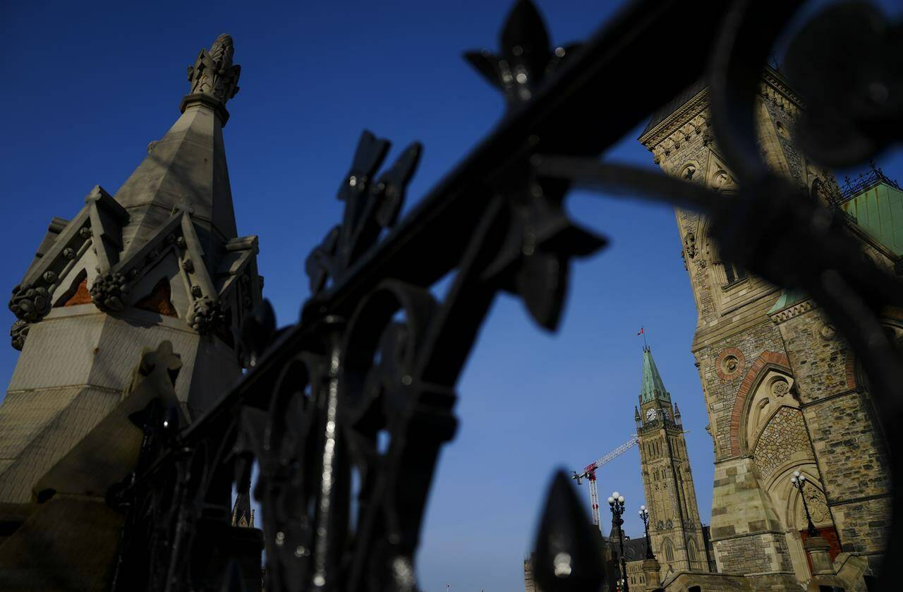 The Liberal government will extend a program that funds 400 local reporting jobs across the country. The Peace Tower of Parliament Hill is pictured through the iron fence along Wellington Street in Ottawa on Tuesday, Feb. 27, 2024. THE CANADIAN PRESS/Sean Kilpatrick