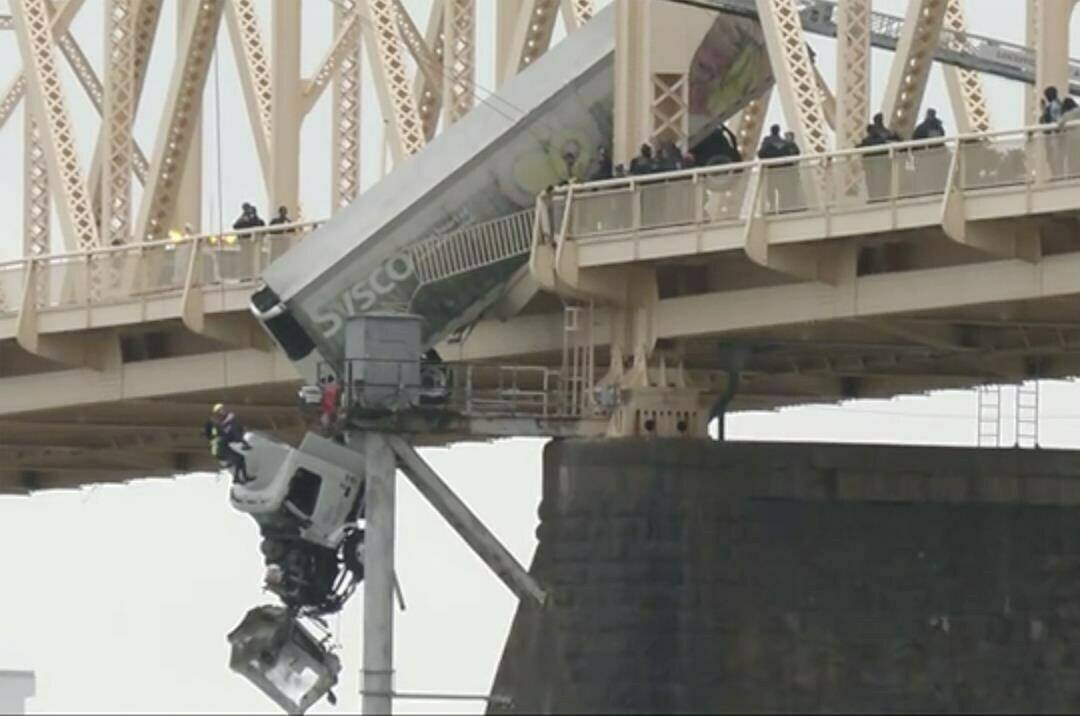 Louisville emergency crews rescue the driver of semitruck that is dangling off the Clark Memorial Bridge over the Ohio River on Friday, March 1, 2024 in Louisville, Ky. The driver was pulled to safety by firefighters following the three-vehicle crash on the bridge connecting Louisville, Kentucky to southern Indiana. (WDRB via AP)