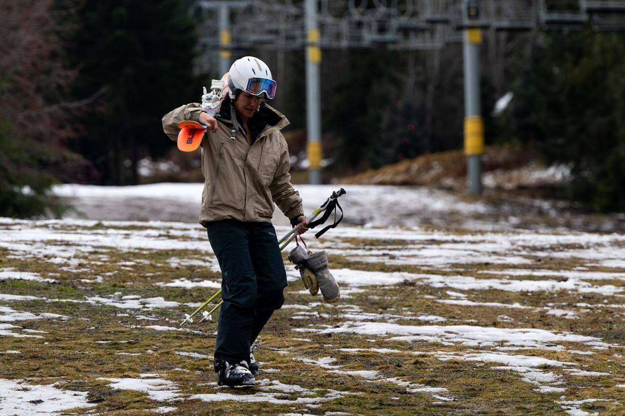 As spring break nears, resorts across Canada are working to cover up green patches and make their terrain skiable enough to entice their usual holiday visitors. A skier walks down a patchy ski slope in Whistler, B.C., Friday, Dec. 29, 2023. THE CANADIAN PRESS/Ethan Cairns