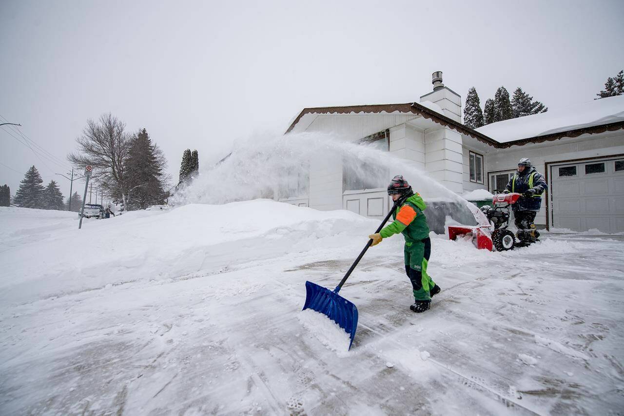People use snowblowers and shovels on their walkways and driveways during a Winter Storm Warning in Saskatoon, Sask., Sunday, March 3, 2024. The city saw large amount of snow and strong winds. THE CANADIAN PRESS/Liam Richards