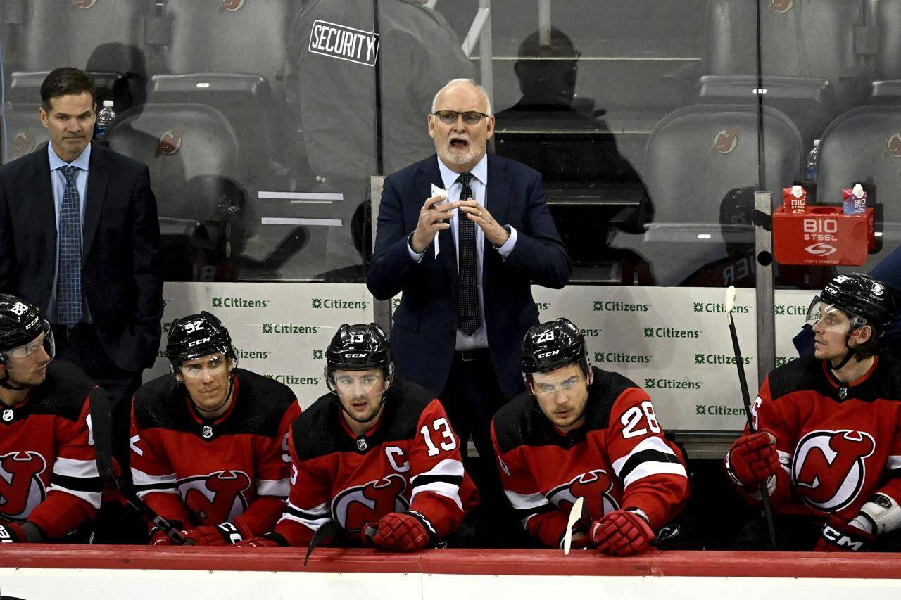 New Jersey Devils coach Lindy Ruff signals for a timeout during the third period of the team’s NHL hockey game against the Calgary Flames on Thursday, Feb. 8, 2024, in Newark, N.J. (AP Photo/Bill Kostroun)