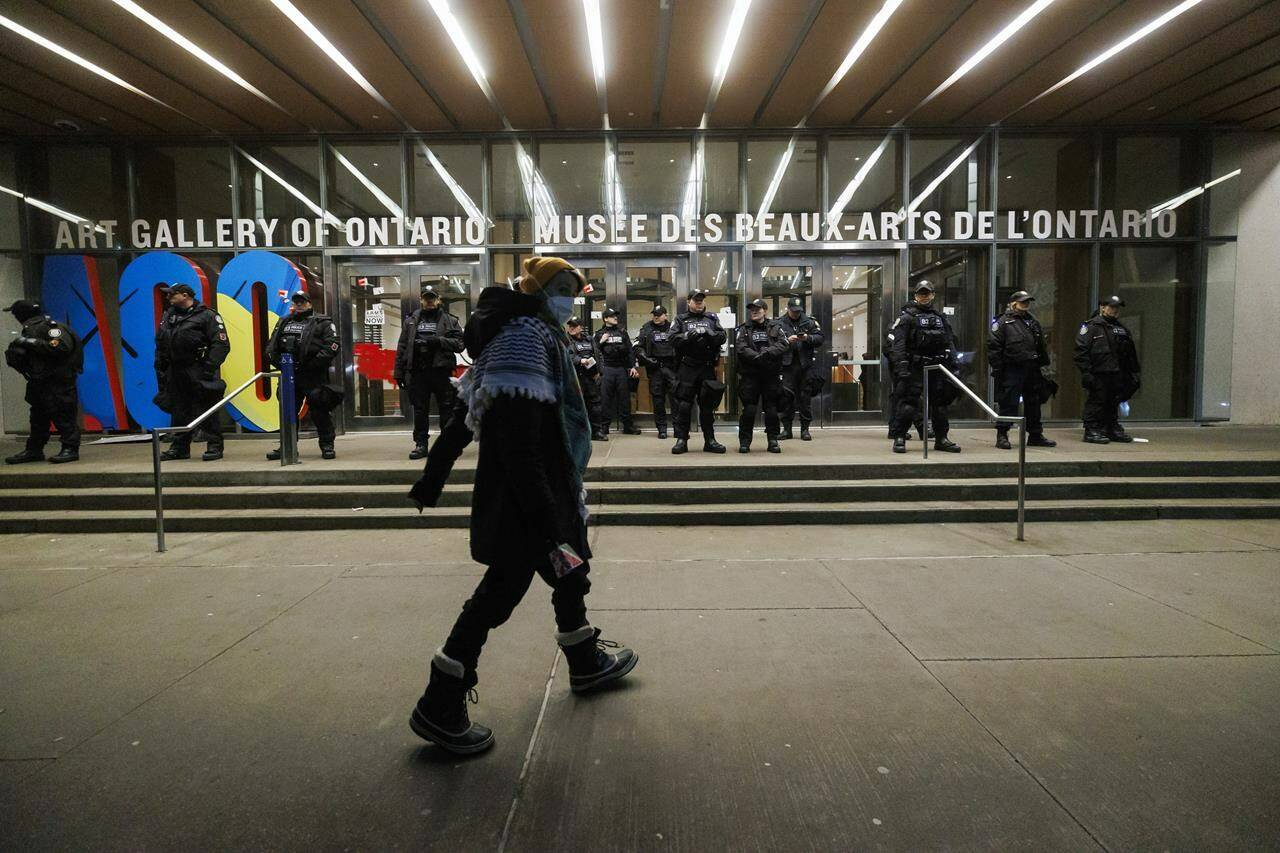 A protester walks as police line the entrance to the Art Gallery of Ontario, where a cancelled event for Canada’s Prime Minister Justin Trudeau and Italy’s Prime Minister Giorgia Meloni, was to take place, in Toronto, Saturday, Mar. 2, 2024. THE CANADIAN PRESS/Cole Burston