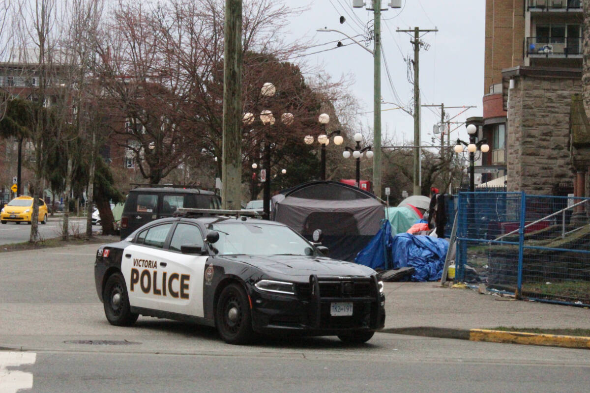 A Victoria Police officer pulls off the sidewalk leaving an encampment of people experiencing homelessness on Pandora Ave. in Victoria on Thursday, Feb. 29. (Mark Page/News Staff)
