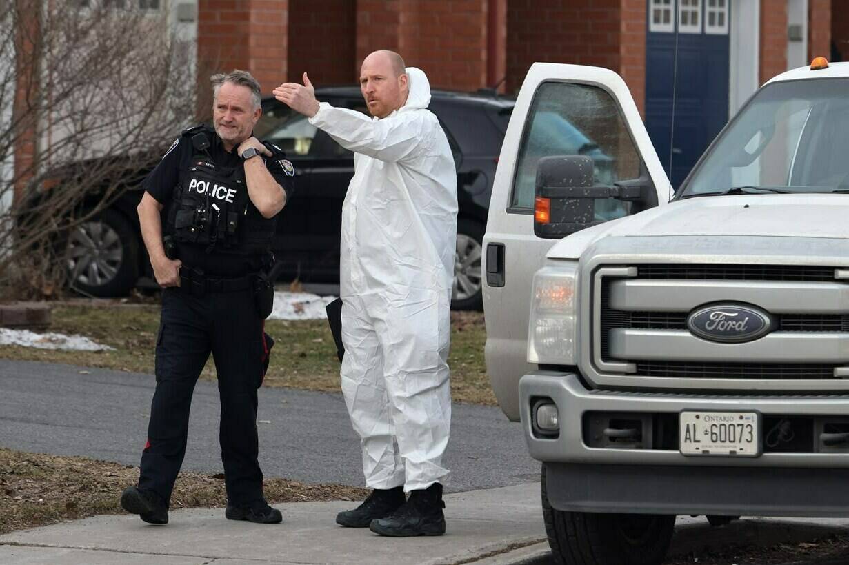 A police officer and a member of the coroner’s office talk at the scene of a homicide where six people were found dead in the Barrhaven suburb of Ottawa on Thursday, March 7, 2024. THE CANADIAN PRESS/ Patrick Doyle