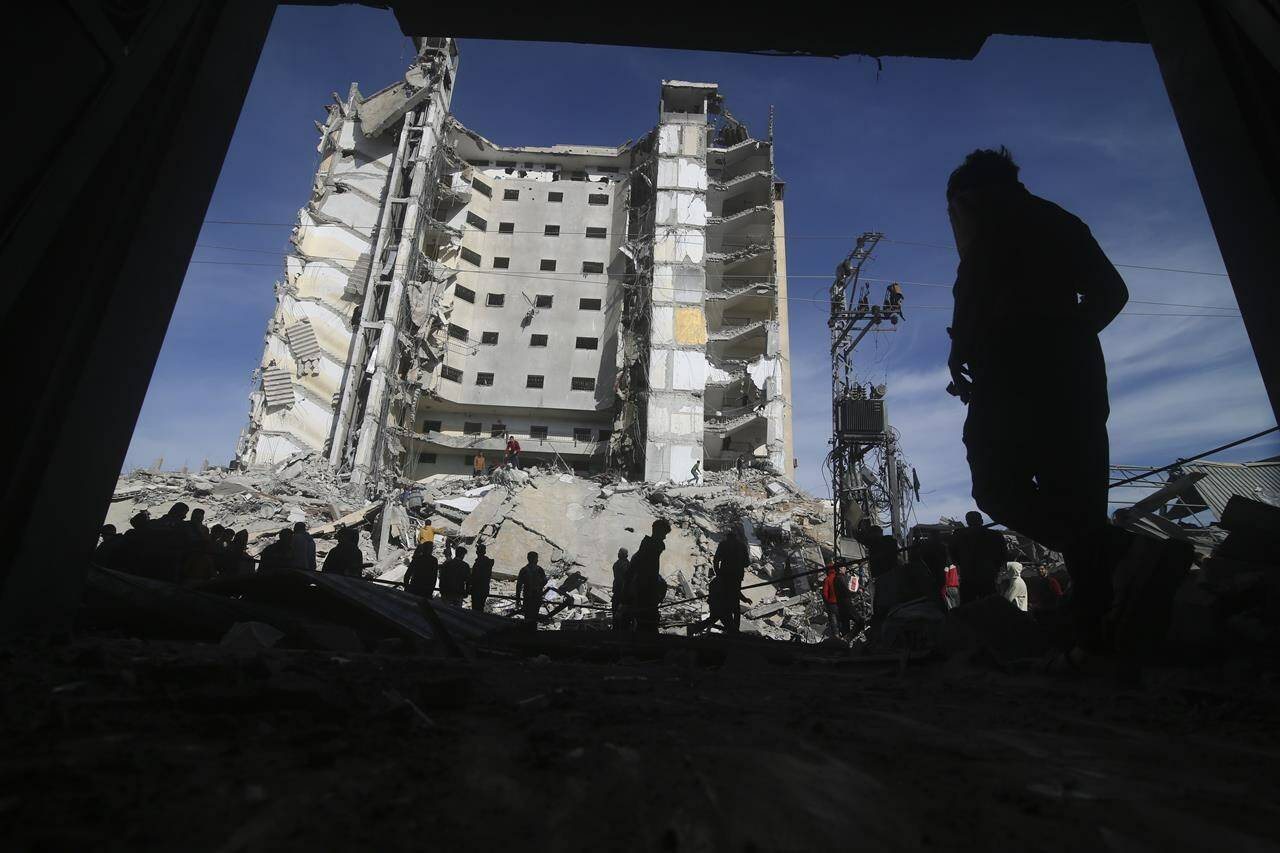 Palestinians walk by a residential building destroyed in an Israeli strike in Rafah, Gaza Strip on March 9, 2024. THE CANADIAN PRESS/AP, Hatem Ali