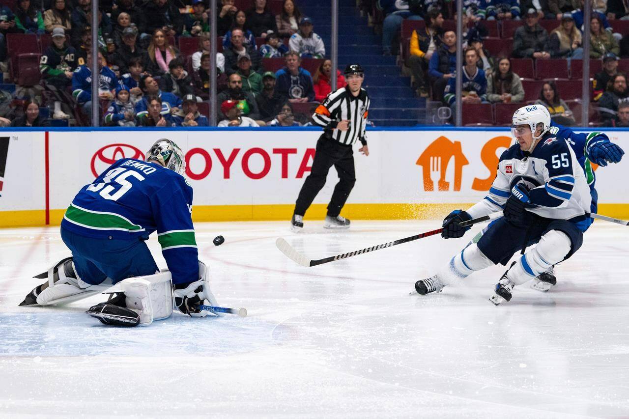 All-star goalie Thatcher Demko was absent from Vancouver Canucks practice Tuesday, days after suddenly leaving a game. Demko (35) stops Winnipeg Jets’ Mark Scheifele (55) as Vancouver’s Carson Soucy (7) watches during the second period of an NHL game, in Vancouver, Saturday, March 9, 2024. THE CANADIAN PRESS/Ethan Cairns