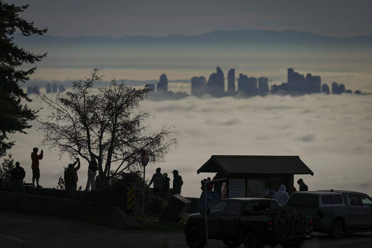 Dozens of high temperature records were broken across British Columbia Saturday. People are silhouetted at the Cypress Mountain Lookout in West Vancouver, B.C., while viewing fog blanketing the Metro Vancouver area, Sunday, Nov. 26, 2023. THE CANADIAN PRESS/AP-Darryl Dyck.
