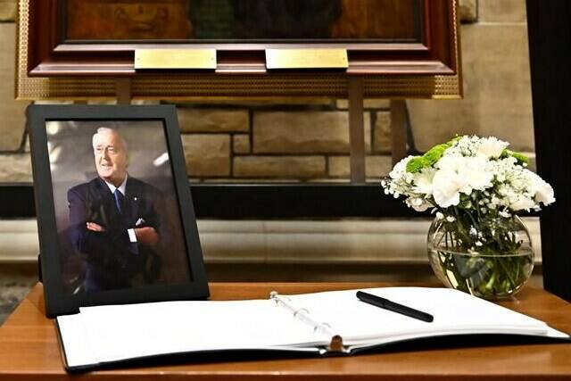 Members of the public who wish to pay tribute to Brian Mulroney can visit his casket in Ottawa starting this afternoon. A photograph and book of condolences for Members of Parliament to sign are seen in front of the official portrait of former prime minister Brian Mulroney, in the antechamber to the House of Commons on Parliament Hill, Ottawa, Friday, March 1, 2024. THE CANADIAN PRESS/Justin Tang