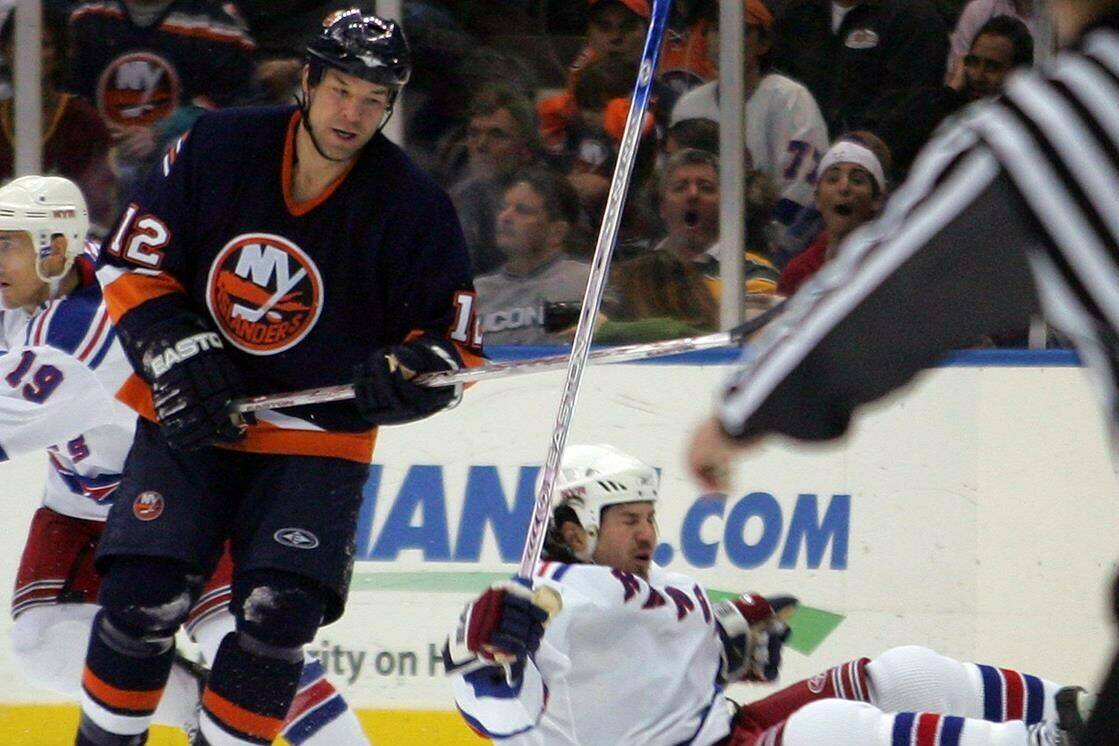 New York Rangers’ Ryan Hollweg lands on the ground after being hit by New York Islanders’ Chris Simon (12) during the third period of their hockey game, Thursday, March 8, 2007, at Nassau Coliseum in Uniondale, N.Y. Simon’s family says the late NHL enforcer died by suicide. And it “strongly believes” a progressive and fatal disease associated with repeated traumatic brain injuries is to blame. THE CANADIAN PRESS/AP/Ed Betz