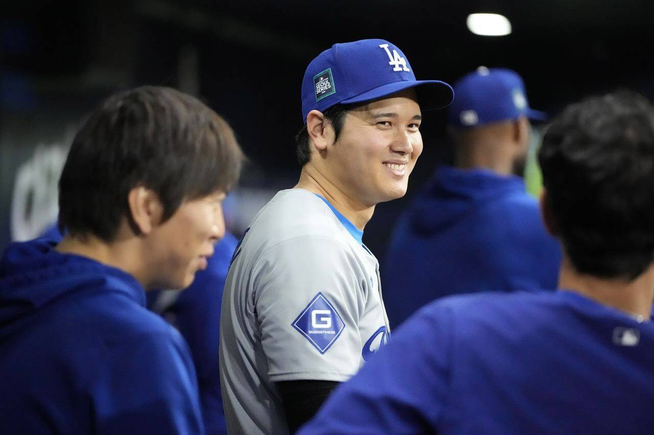 Los Angeles Dodgers designated hitter Shohei Ohtani, center, smiles as he stands in the dugout during the ninth inning of an opening day baseball game against the San Diego Padres at the Gocheok Sky Dome in Seoul, South Korea Wednesday, March 20, 2024, in Seoul, South Korea. (AP Photo/Lee Jin-man)