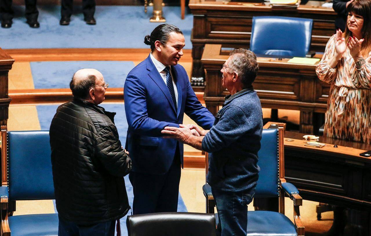 Manitoba Premier Wab Kinew, centre, apologizes to Richard Beauvais, right, and Edward Ambrose, left, in the Manitoba Legislature in Winnipeg, Manitoba on Thursday, March 21, 2024. Ambrose and Beauvais were switched at birth in hospital in 1955. THE CANADIAN PRESS/John Woods