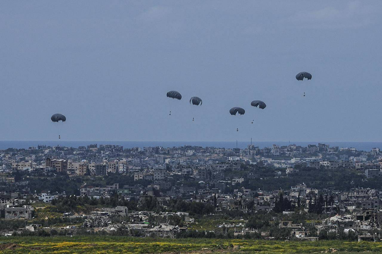Parachutes drop supplies into the northern Gaza Strip, as seen from southern Israel, Sunday, March 24, 2024. (AP Photo/Tsafrir Abayov)